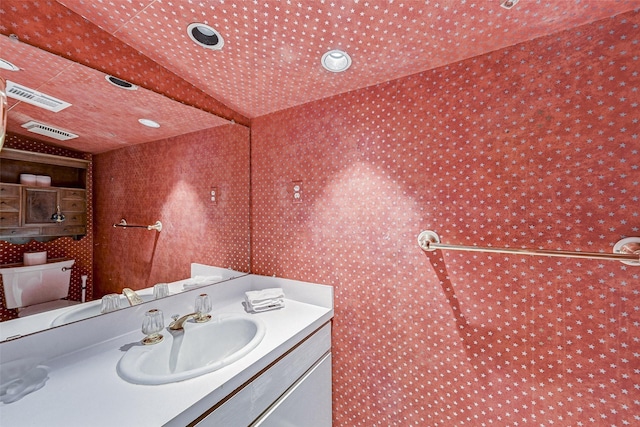 bathroom with vanity, toilet, and vaulted ceiling