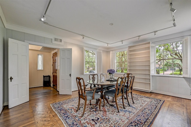 dining space featuring hardwood / wood-style floors, crown molding, and plenty of natural light