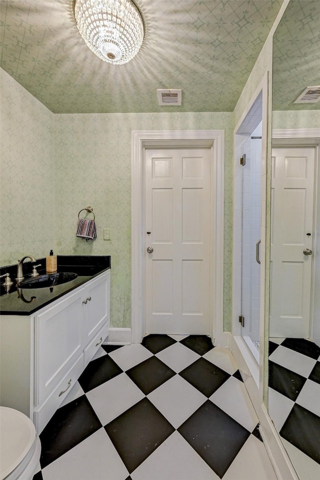 interior space featuring vanity, toilet, an enclosed shower, and a notable chandelier