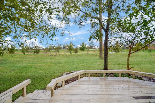 wooden terrace featuring a rural view and a lawn