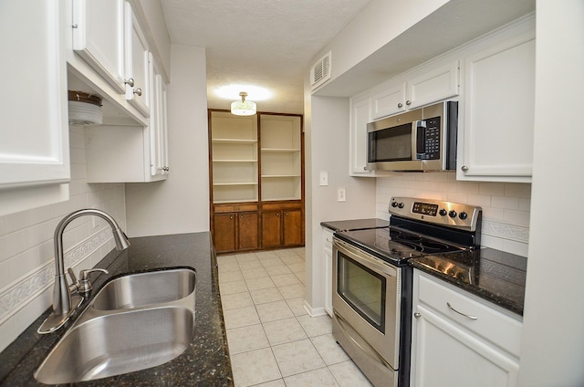 kitchen with light tile patterned flooring, sink, dark stone counters, stainless steel appliances, and white cabinets