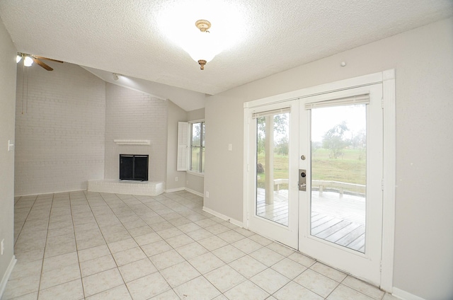 unfurnished living room with vaulted ceiling, a wealth of natural light, a fireplace, and light tile patterned floors