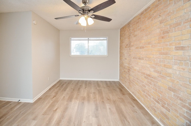 empty room with ceiling fan, light hardwood / wood-style flooring, a textured ceiling, and brick wall