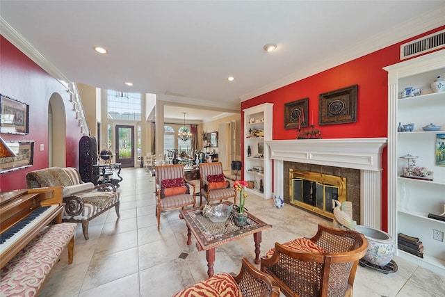 living room featuring a tile fireplace, ornamental molding, light tile patterned floors, and built in shelves