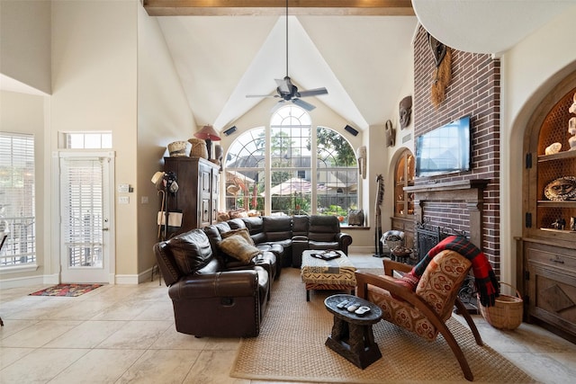 tiled living room featuring a brick fireplace, ceiling fan, and a high ceiling