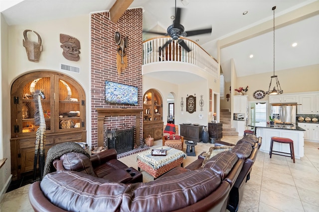 tiled living room featuring beamed ceiling, ceiling fan, high vaulted ceiling, and a brick fireplace