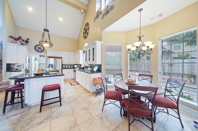 dining space with light tile patterned floors, a wealth of natural light, high vaulted ceiling, and a chandelier