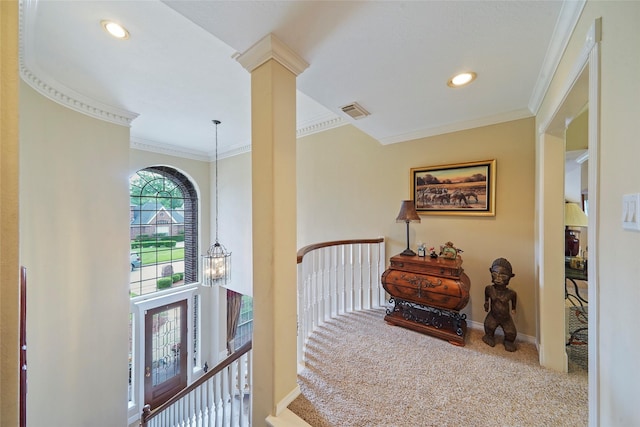 hall with crown molding, a chandelier, decorative columns, and carpet