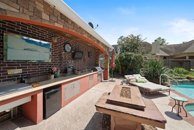 view of patio with an outdoor kitchen, a grill, a fenced in pool, and a fire pit