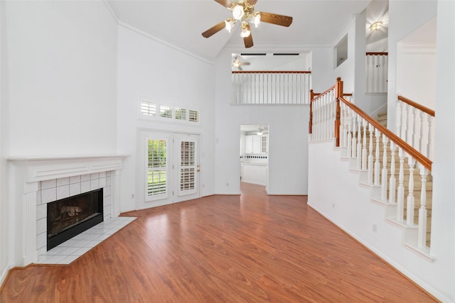 unfurnished living room with a tile fireplace, ornamental molding, ceiling fan, and light hardwood / wood-style floors