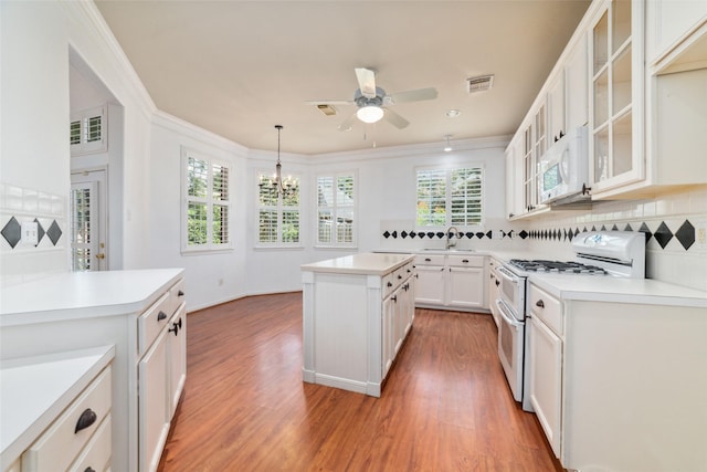 kitchen featuring white cabinetry, tasteful backsplash, a kitchen island, pendant lighting, and white appliances