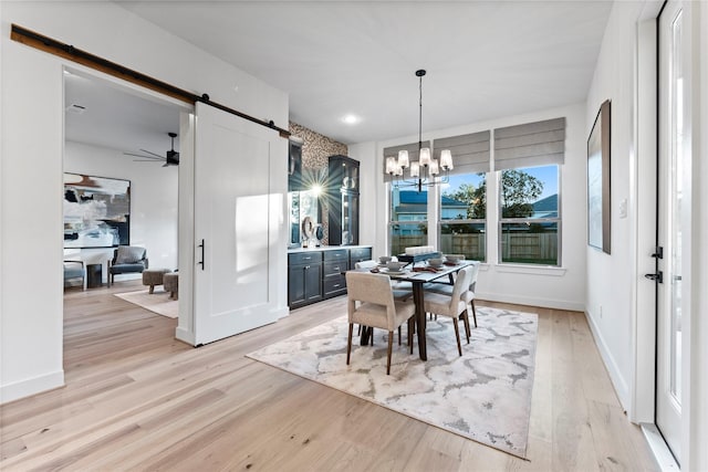 dining space with a barn door, light hardwood / wood-style flooring, and a notable chandelier