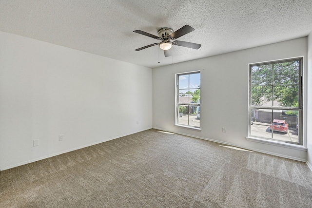 carpeted empty room featuring ceiling fan, baseboards, and a textured ceiling