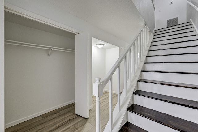 stairs with visible vents, baseboards, and wood finished floors