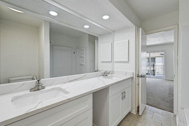 2022 Lakewood Ct, Willis, TX 77318 - bathroom featuring a textured ceiling, double vanity, a sink, and recessed lighting