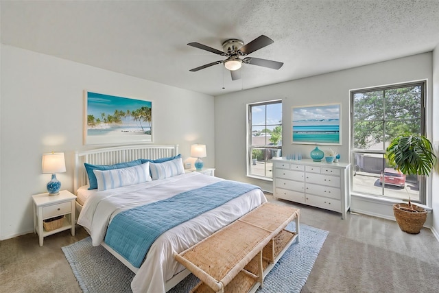 bedroom featuring ceiling fan, a textured ceiling, baseboards, and carpet flooring