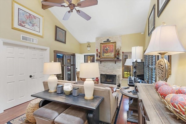 living room with high vaulted ceiling, ceiling fan, hardwood / wood-style floors, a fireplace, and beamed ceiling