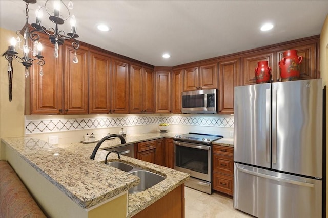 kitchen featuring sink, light stone counters, decorative light fixtures, stainless steel appliances, and kitchen peninsula