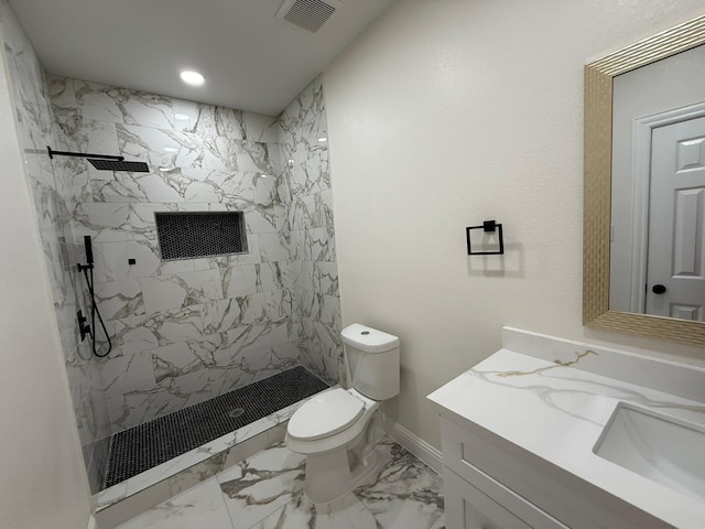 bathroom featuring vanity, a tile shower, and toilet