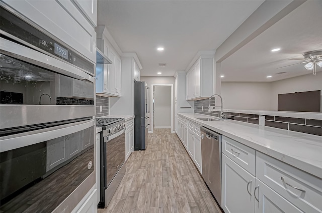 kitchen featuring sink, white cabinetry, light hardwood / wood-style flooring, stainless steel appliances, and backsplash