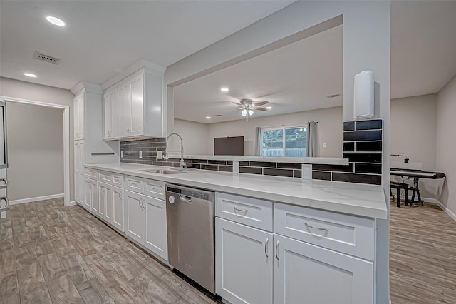 kitchen featuring sink, light wood-type flooring, stainless steel dishwasher, white cabinets, and backsplash