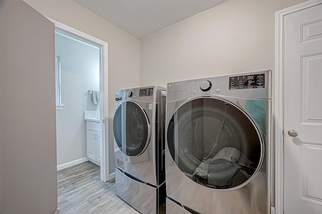 laundry room with light hardwood / wood-style floors, cabinets, and washing machine and clothes dryer