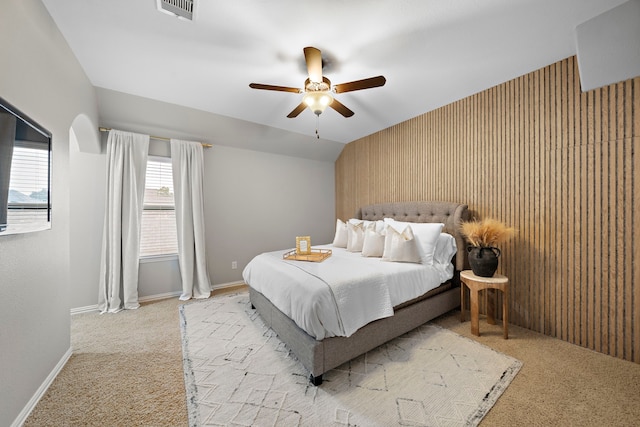 bedroom featuring ceiling fan, lofted ceiling, wooden walls, and light colored carpet