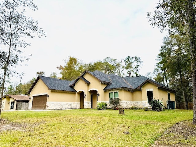 view of front of home with a garage, a front yard, and central AC unit