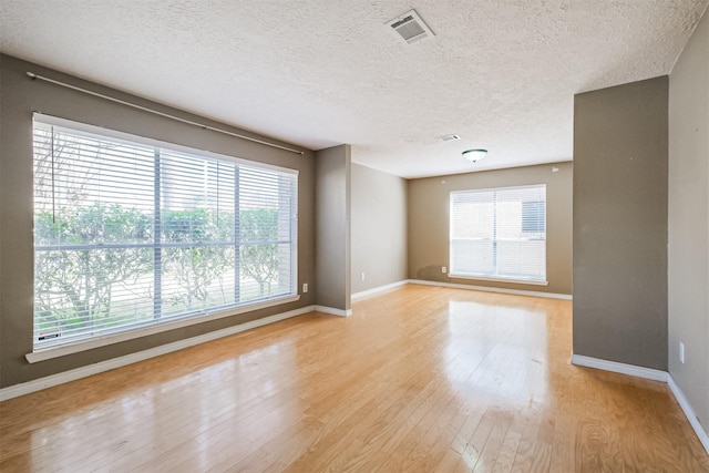 unfurnished room featuring light hardwood / wood-style floors and a textured ceiling