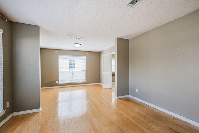 spare room with a textured ceiling and light wood-type flooring