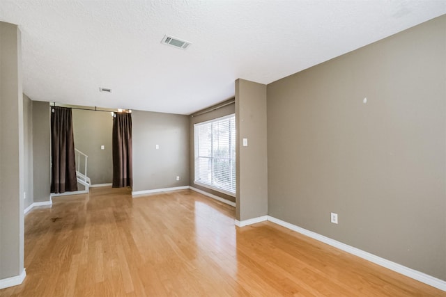 empty room with light hardwood / wood-style flooring and a textured ceiling