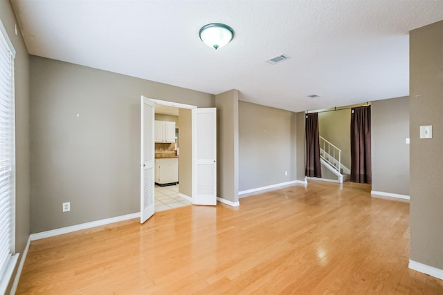 empty room featuring a textured ceiling and light wood-type flooring