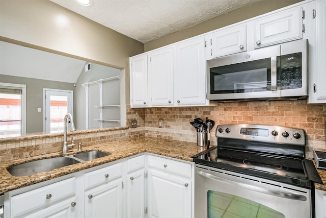 kitchen featuring dark stone countertops, appliances with stainless steel finishes, sink, and white cabinets