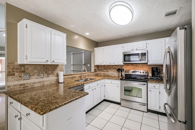 kitchen featuring sink, white cabinetry, dark stone countertops, stainless steel appliances, and kitchen peninsula