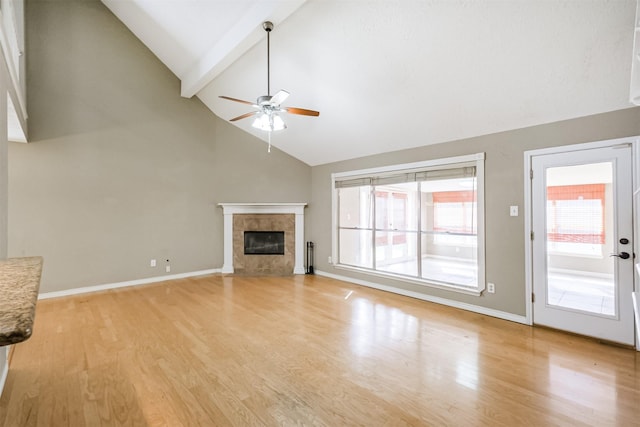 unfurnished living room with ceiling fan, high vaulted ceiling, a fireplace, light hardwood / wood-style floors, and beamed ceiling