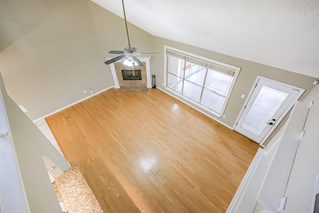 unfurnished living room featuring ceiling fan, light hardwood / wood-style floors, vaulted ceiling, and a textured ceiling