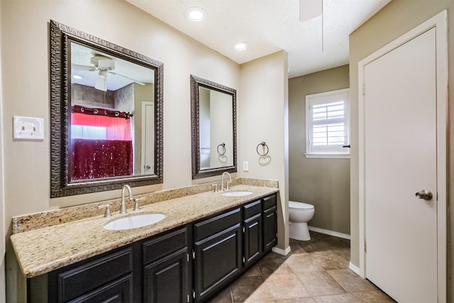 bathroom with ceiling fan, vanity, toilet, and a textured ceiling