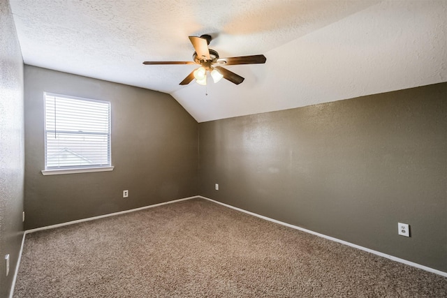 carpeted empty room with ceiling fan, lofted ceiling, and a textured ceiling