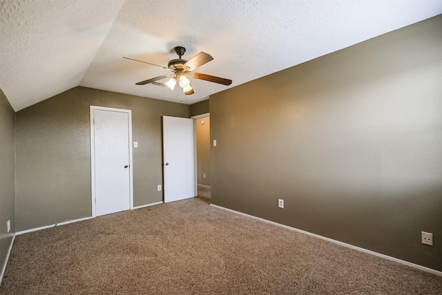 unfurnished bedroom featuring ceiling fan, lofted ceiling, carpet floors, and a textured ceiling