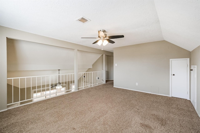 spare room featuring a textured ceiling, vaulted ceiling, ceiling fan, and carpet flooring