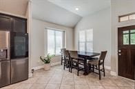 tiled dining area featuring vaulted ceiling