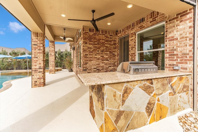 view of patio featuring ceiling fan, an outdoor kitchen, a grill, and exterior bar