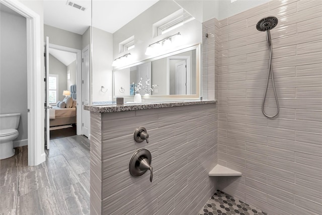 bathroom with a tile shower and toilet