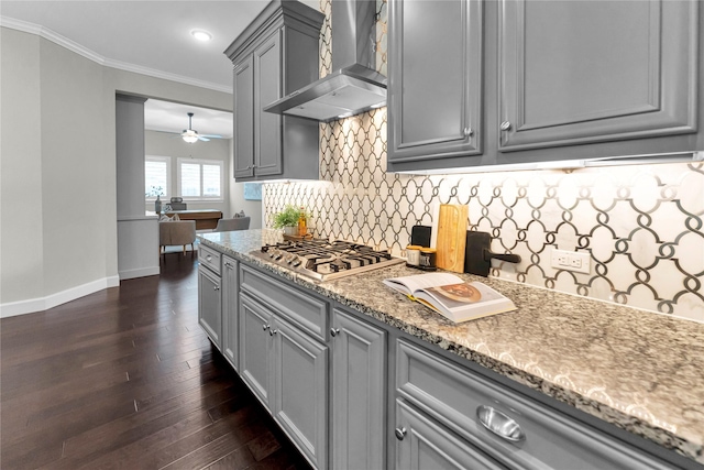 kitchen featuring wall chimney range hood, crown molding, gray cabinets, stone counters, and stainless steel gas stovetop