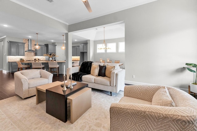 living room featuring ceiling fan with notable chandelier, light hardwood / wood-style flooring, and ornamental molding