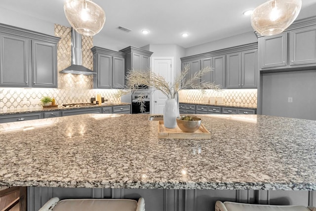 kitchen featuring hanging light fixtures, a kitchen breakfast bar, and wall chimney exhaust hood