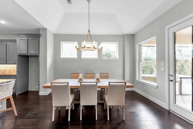 dining space featuring lofted ceiling, dark hardwood / wood-style floors, and a chandelier