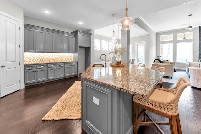 kitchen featuring light stone counters, gray cabinets, sink, and decorative backsplash