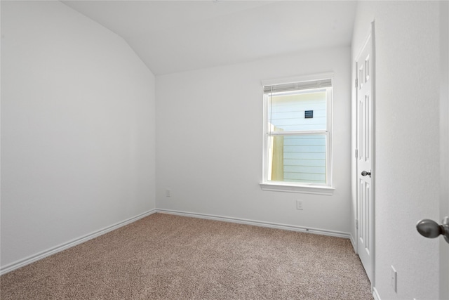 spare room with carpet flooring and vaulted ceiling