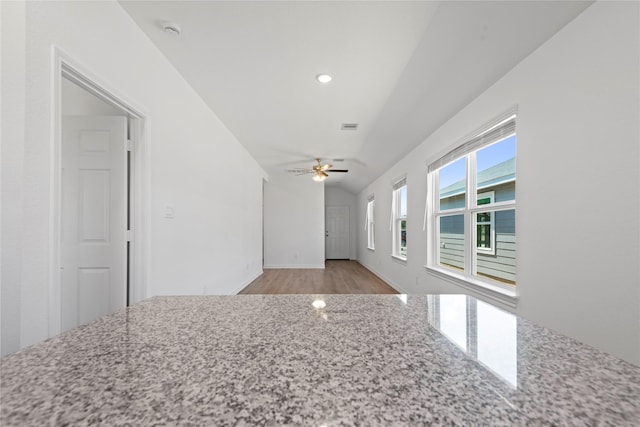 interior space featuring vaulted ceiling, light stone countertops, ceiling fan, and light wood-type flooring